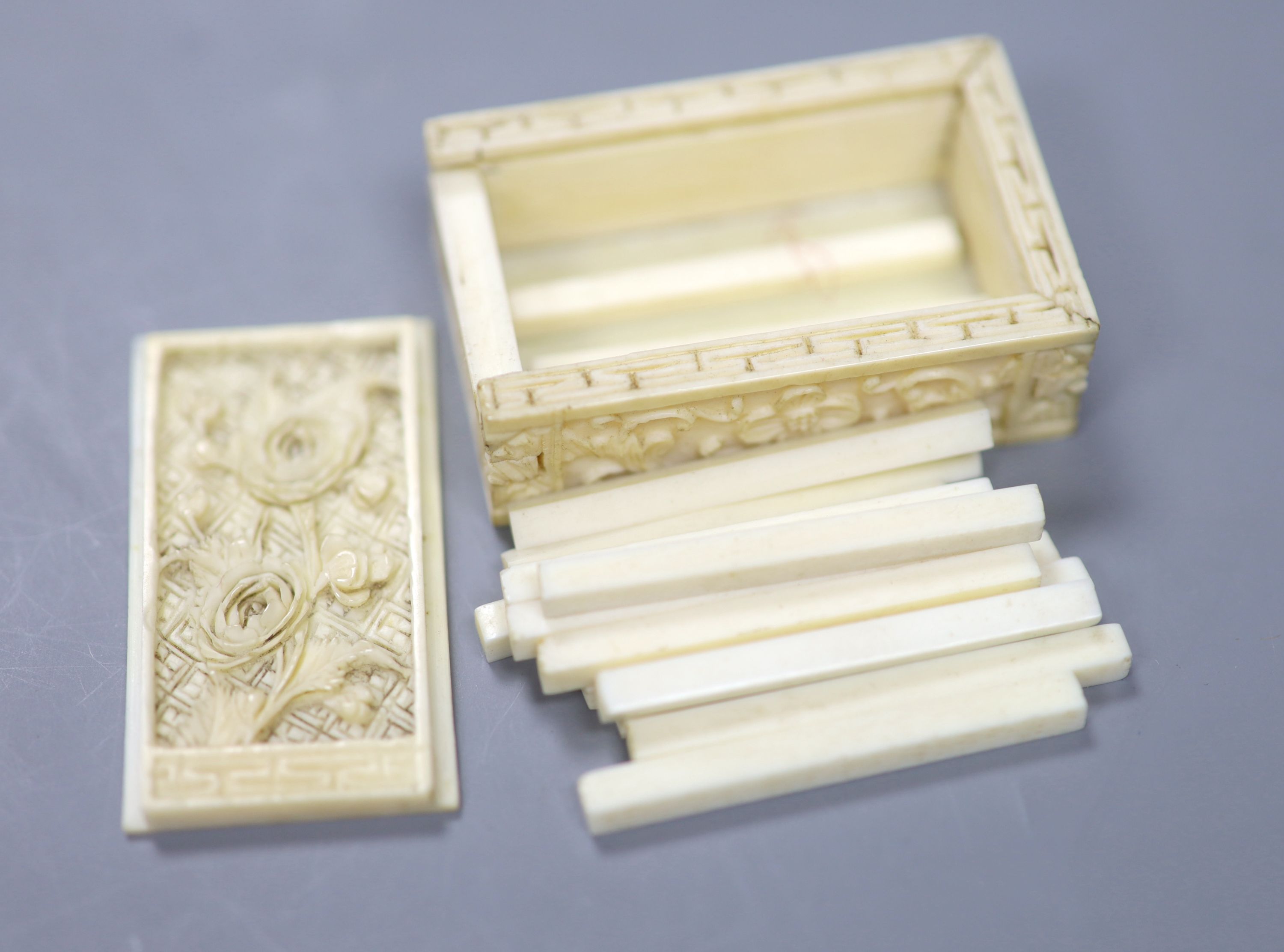 A 19th century Cantonese export carved ivory whist box, with a sliding floral panelled cover, and contents, 5 x 3.5cm together with a